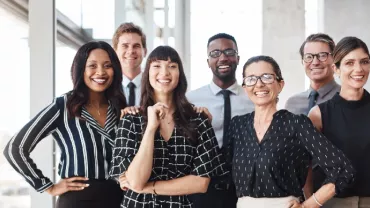 Group of diverse professionals smiling in an office setting.