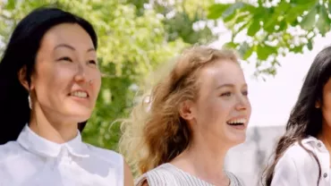 Three women walking outdoors, smiling and enjoying a sunny day.