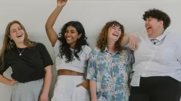 Four people standing together, laughing and smiling.