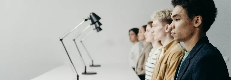 Row of people in profile view behind modern desk lamps.