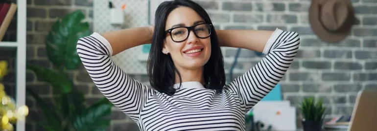 Woman in a striped shirt smiling and relaxing at her workplace.